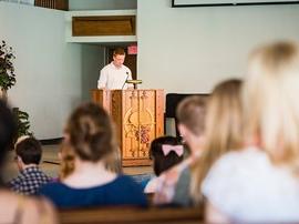 Student reading verses from the bible for chapel.